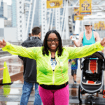 Woman with her arms out as she crosses the finish line in the rain.