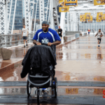 5k Runner pushing a stoller on the bridge in the rain.