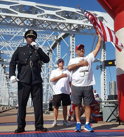 Sgt Clifton Knight standing next to CEO David Davoudpour while they sing the national anthem.