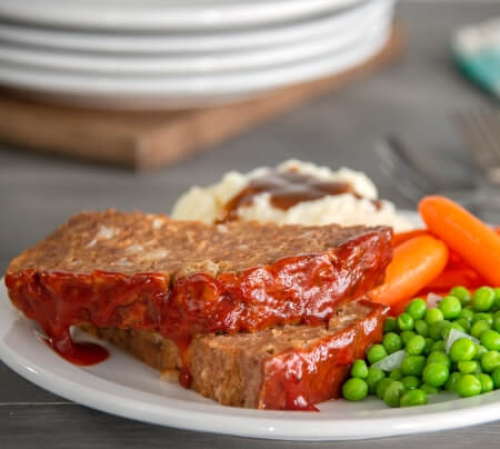 Meatloaf plate with a side of green beans and carrots.